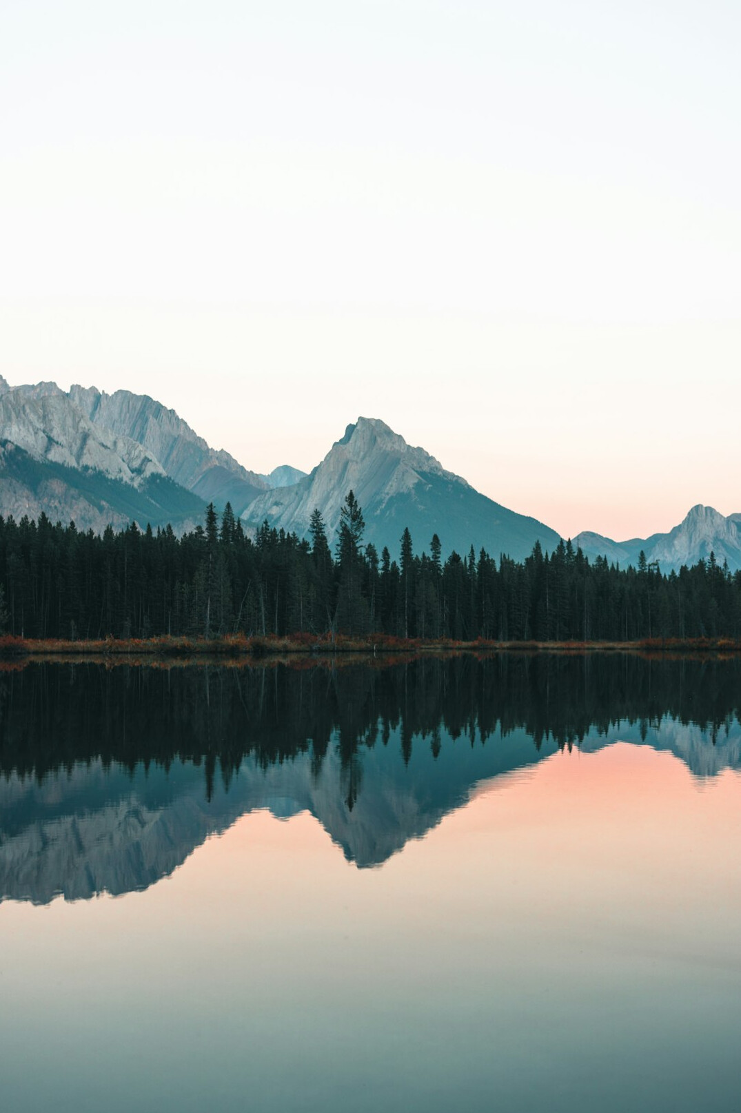 Calm lake with mountains and forest at sunrise